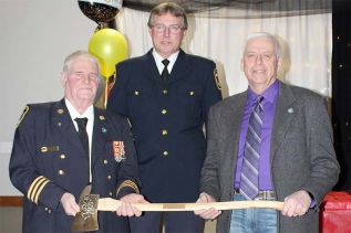 Dep. Chief Bill Babcock was presented with a commemorative fire axe by Dep. Chief Stan Ritchie and Mayor Ron Vandewal Saturday night in Harrowsmith. Photo/Craig Bakay